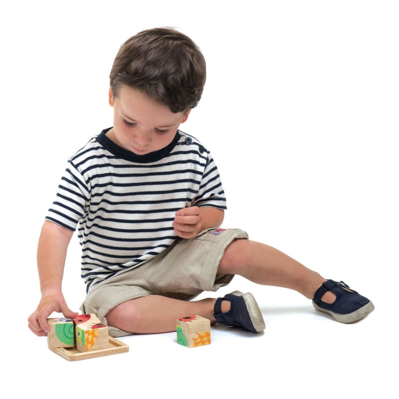 Child playing with 4 block puzzle set by Tender Leaf Toys.