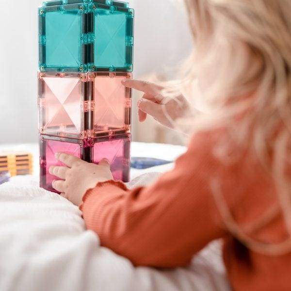 Turquoise, peach and pink magnetic tile tower with child.