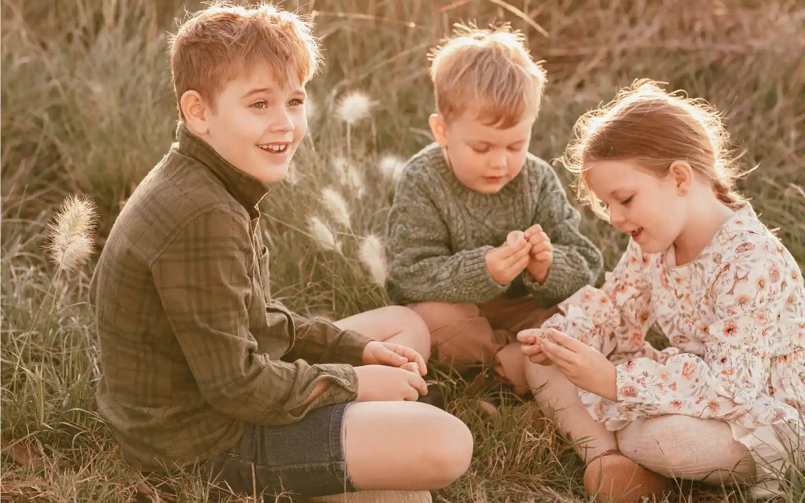 Three children sitting in grass.