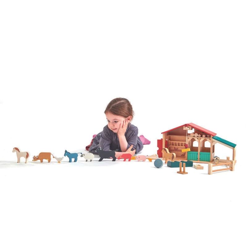 Small child playing with farm set by Tender Leaf Toys
