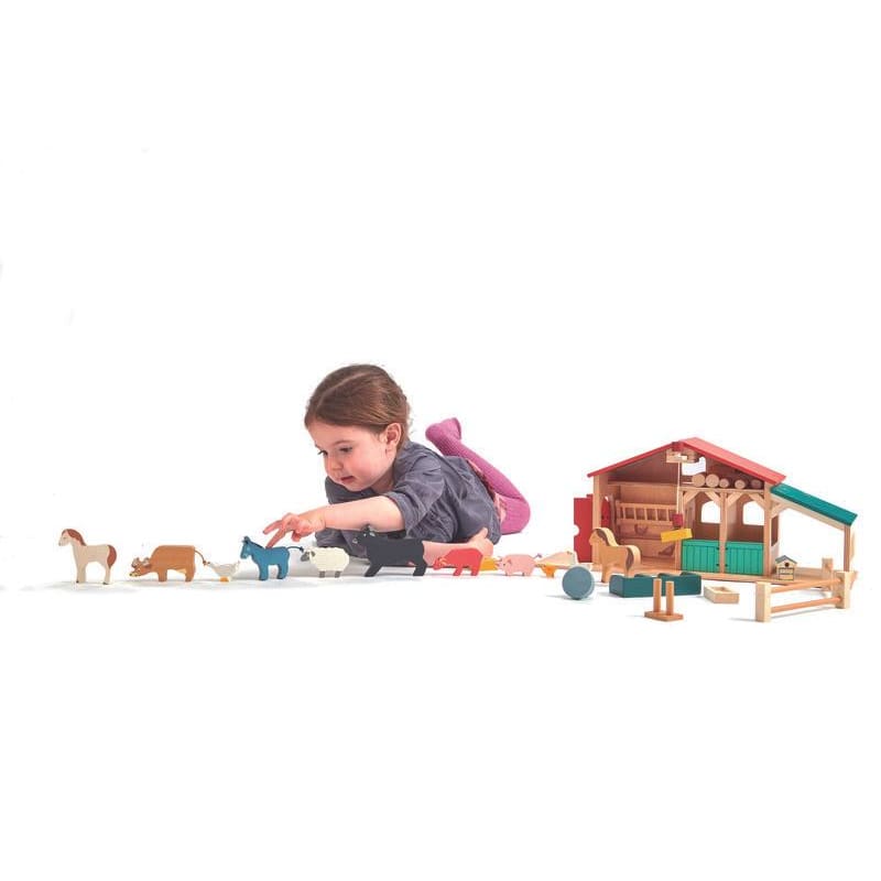 Small shild with wooden toy farm animals from Tender Leaf Toys Farm set